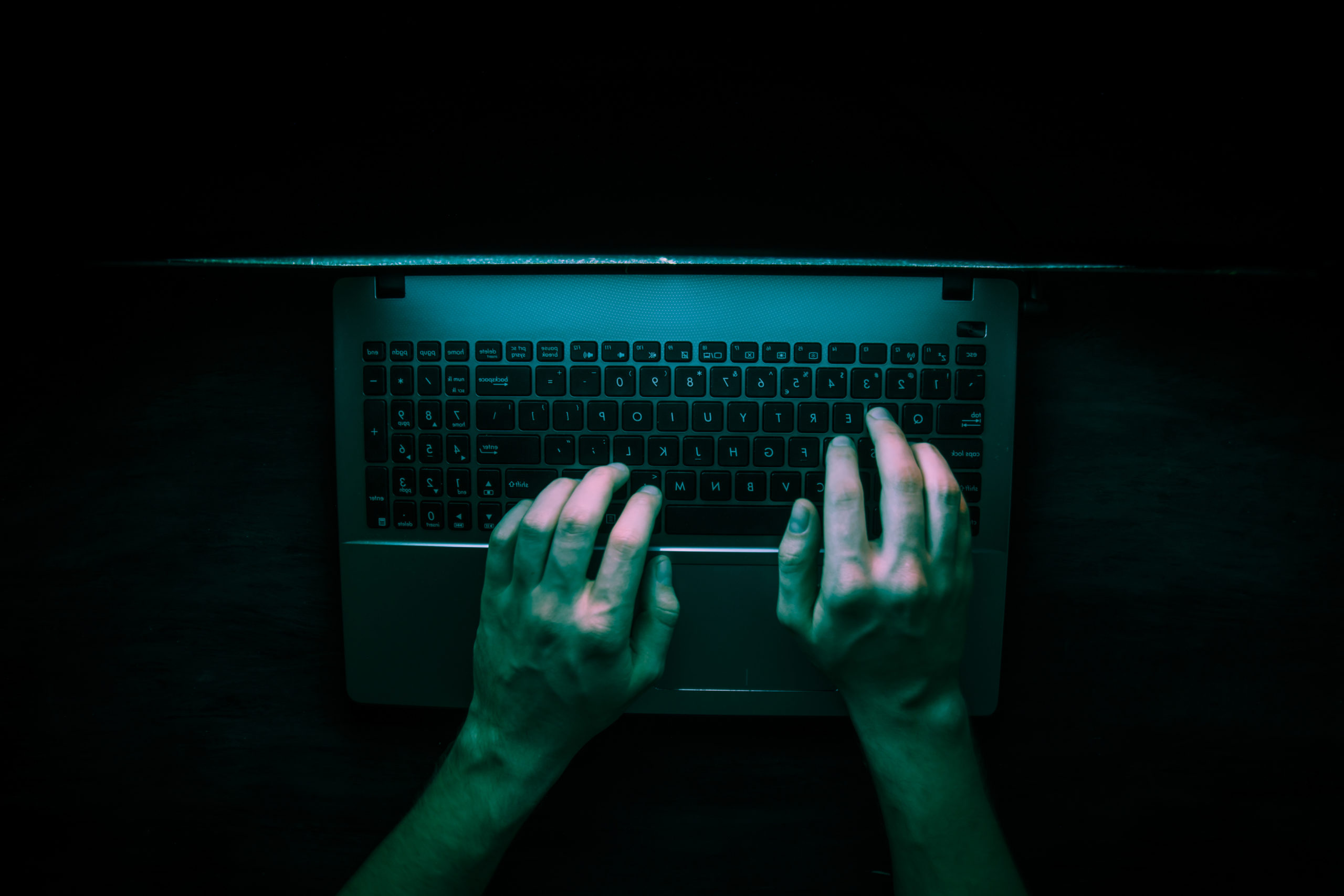 birds-eye view of a hacker on a laptop in the dark
